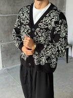 Gilet Triko Paisley – Noir – worn – front view of model holding hands wearing black paisley cardigan sweater